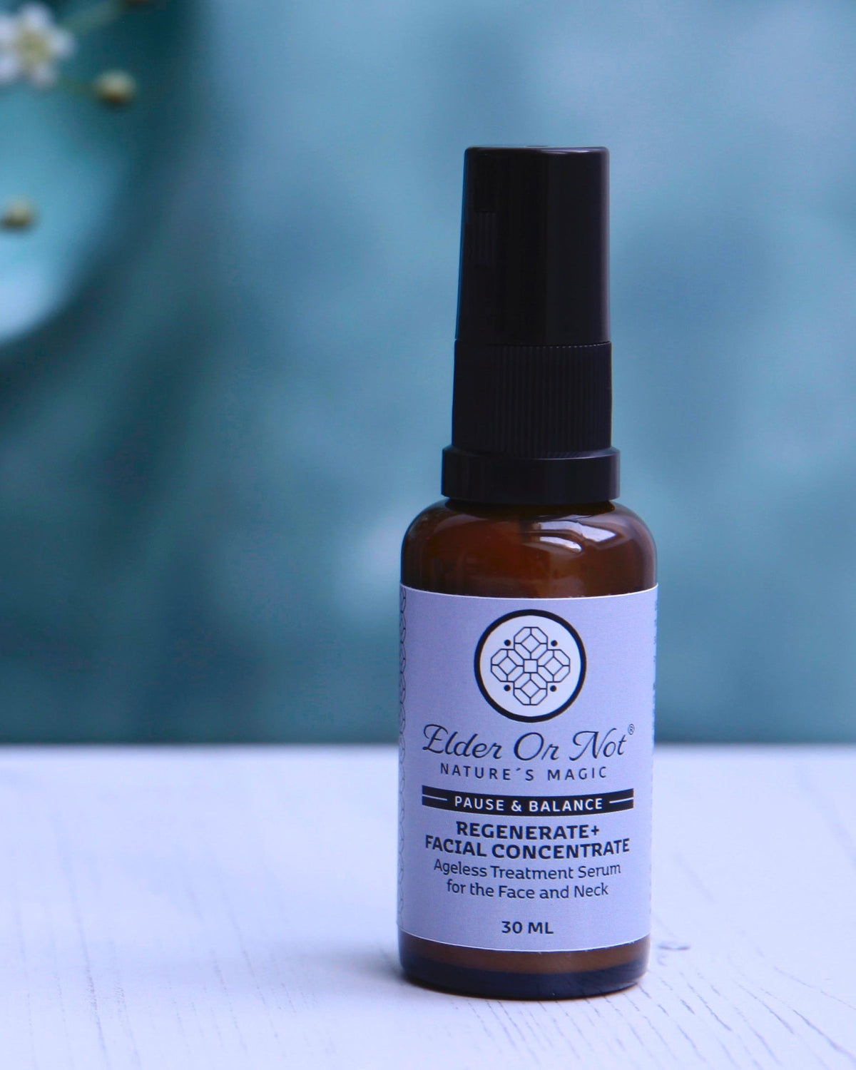 A 30 ml amber glass bottle of Elder Or Not Skincare Regenerate plus Facial Concentrate, featuring a black serum pump,set against a soft teal background.