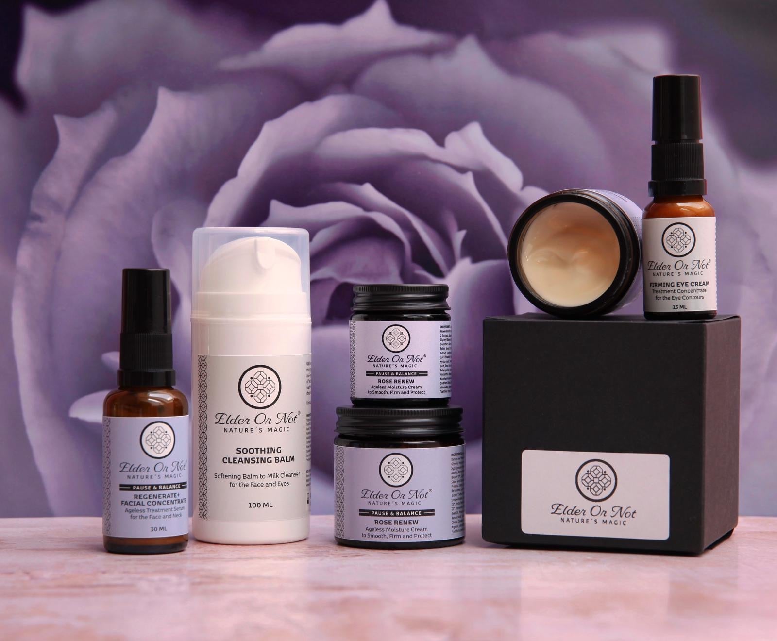 Collection of skincare products with a purple rose in the background