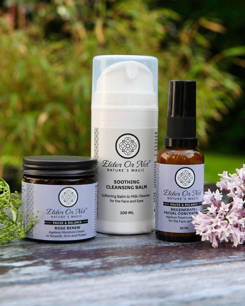 Set of skincare products with lilacs and elderflower buds on a wooden surface outdoors